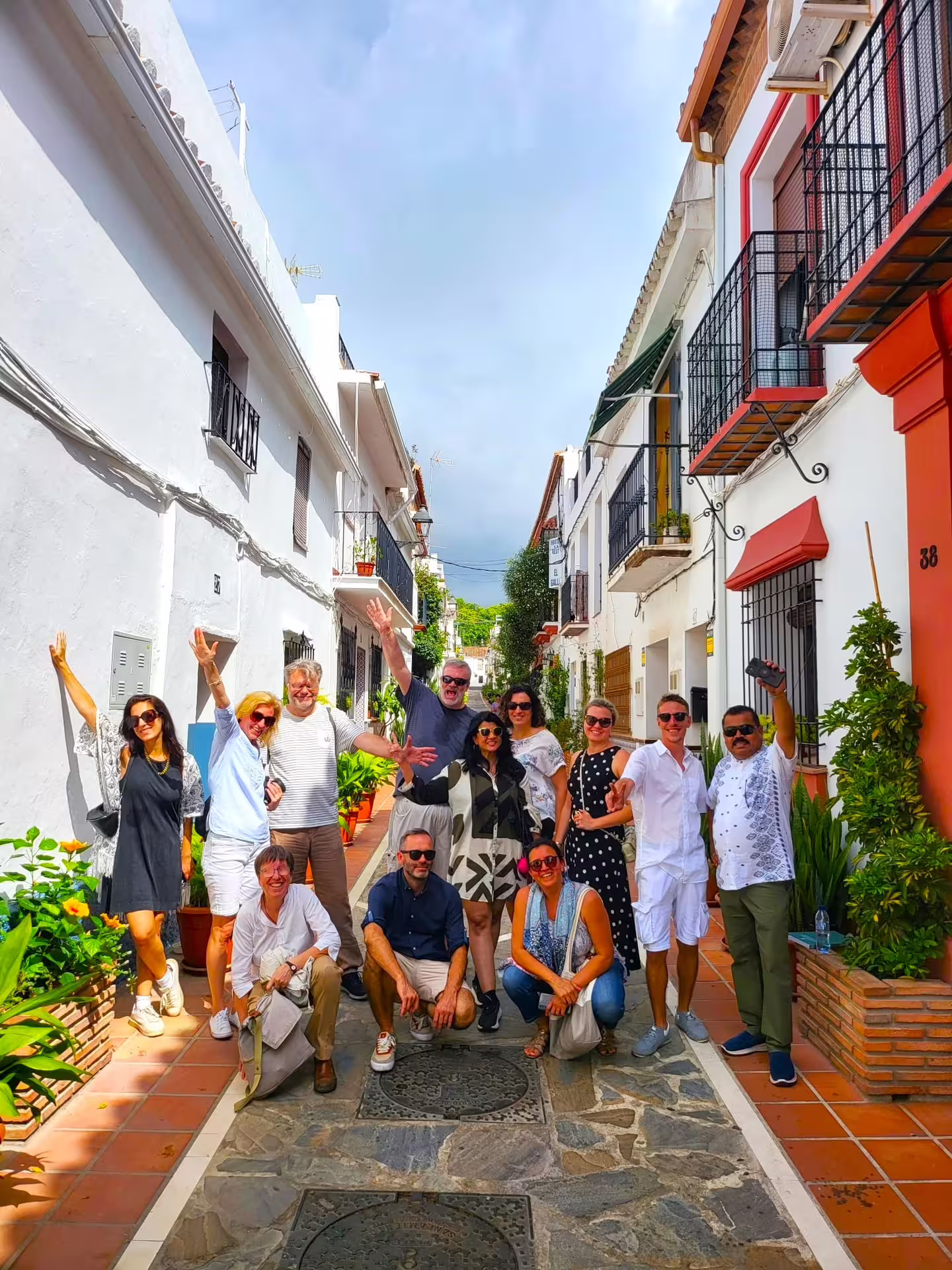 Happy group on Marbella Old Town walking tour in a whitewashed street with balconies and flowers