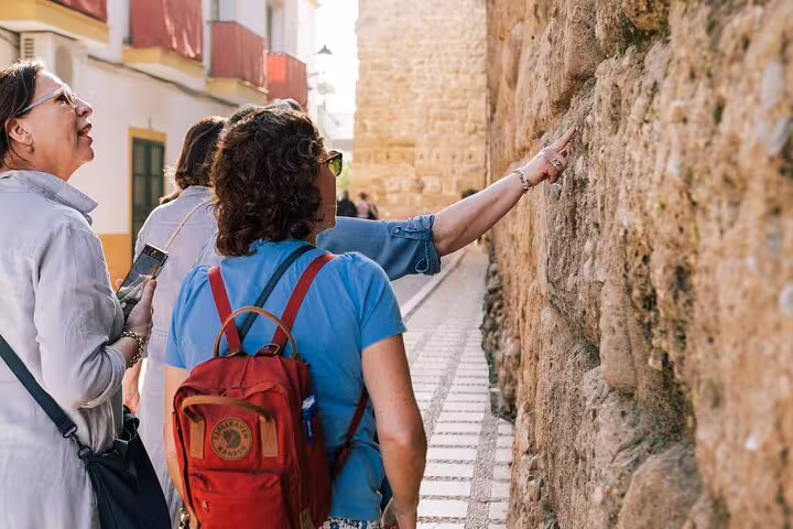 Tourists engage with historic stone walls on a guided walk through Marbella Old Town's charming narrow streets.