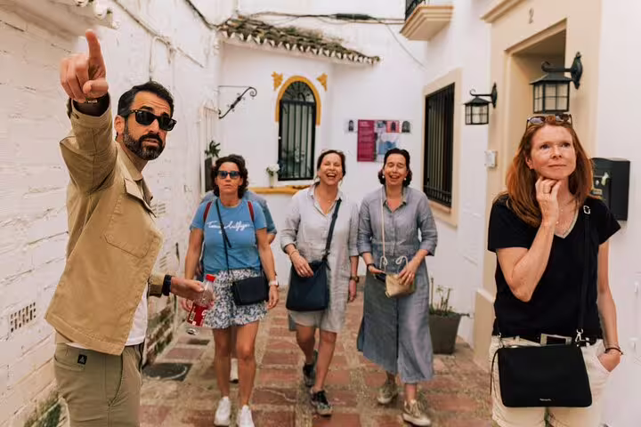 A guide points out historical landmarks to a group in the charming streets of Marbella Old Town during a walking tour.