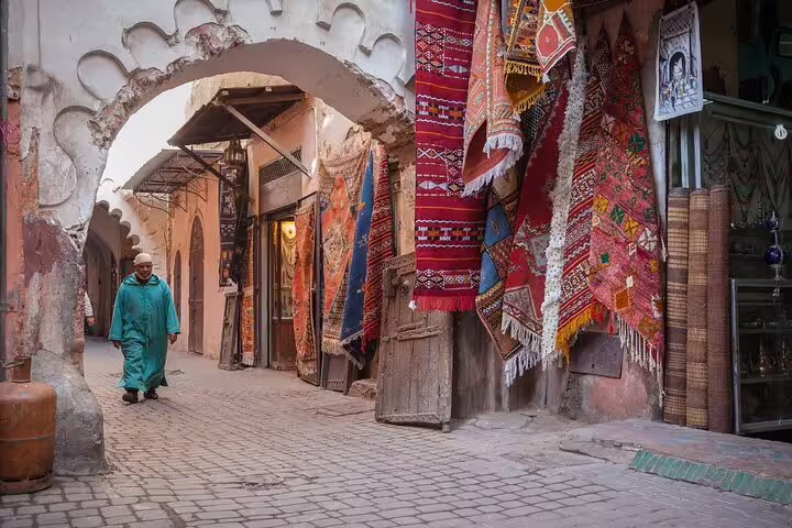 Marrakech medina souk alley with colorful Berber rugs and arched gateway on Morocco 12-day tour