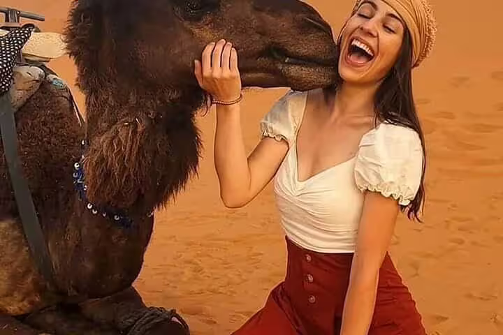 Traveler with camel in Erg Chebbi dunes on 4 days 3 nights desert tour from Marrakech to Merzouga
