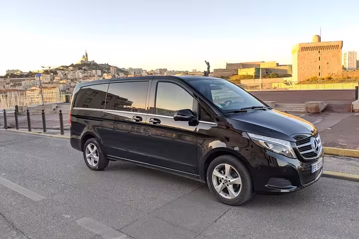 Private Marseille airport to port transfer in black minivan with Old Port skyline at sunset