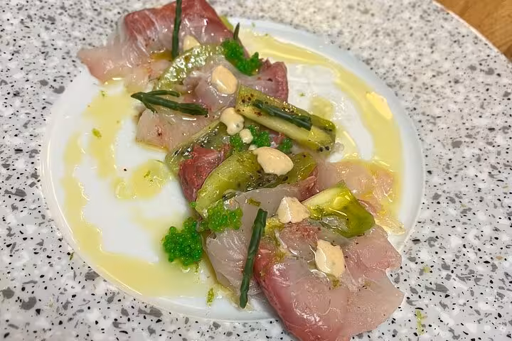 Marseille cooking workshop starter of marinated raw fish with herbs, olive oil and citrus on a speckled plate