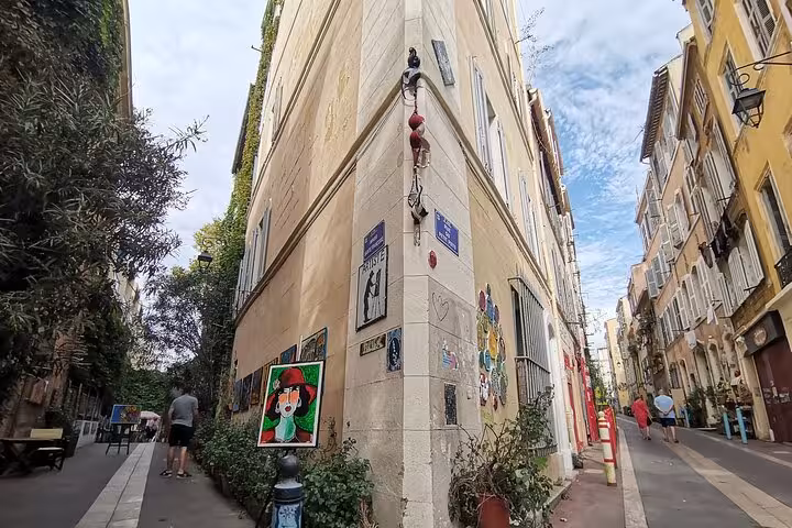 Quiet Marseille street corner with murals and Provençal façades, scenic walk to a pétanque game spot in Le Panier