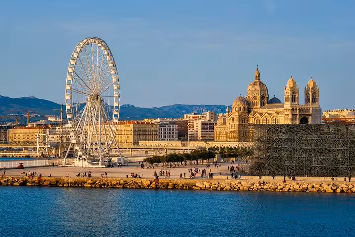 Discover Marseille's vibrant waterfront featuring a Ferris wheel and historic cathedral on a guided city walk.