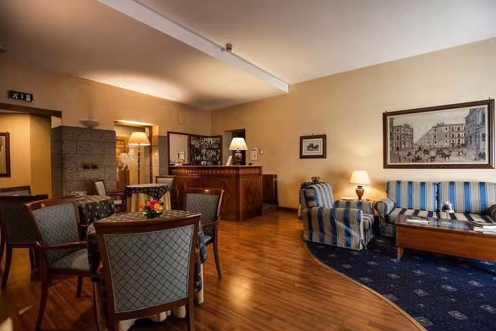 Cozy lobby of Massimo Plaza Hotel Palermo with classic seating area, wooden reception desk and warm ambient lighting