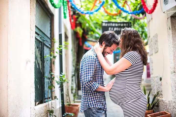 Maternity couple portrait in a Lisbon alley with colorful garlands, private vacation photographer session