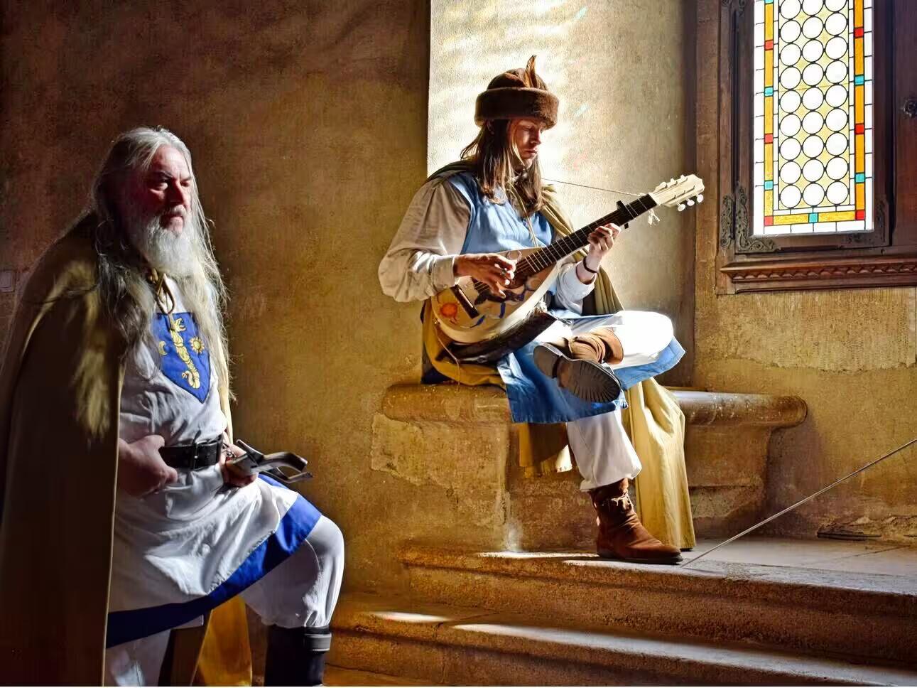 Medieval costumed performers playing lute inside Corvin Castle during a guided tour from Cluj Romania