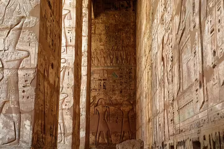 Medinet Habu temple corridor with carved hieroglyphs and pharaoh reliefs on Luxor day tour