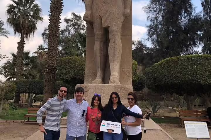 Tour group at Memphis open-air museum posing by colossal Ramses II statue on Pyramids day trip from Cairo