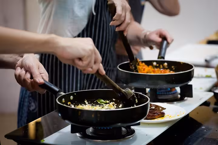 Group of people cooking traditional Argentine dishes in a lively kitchen during a hands-on culinary experience.
