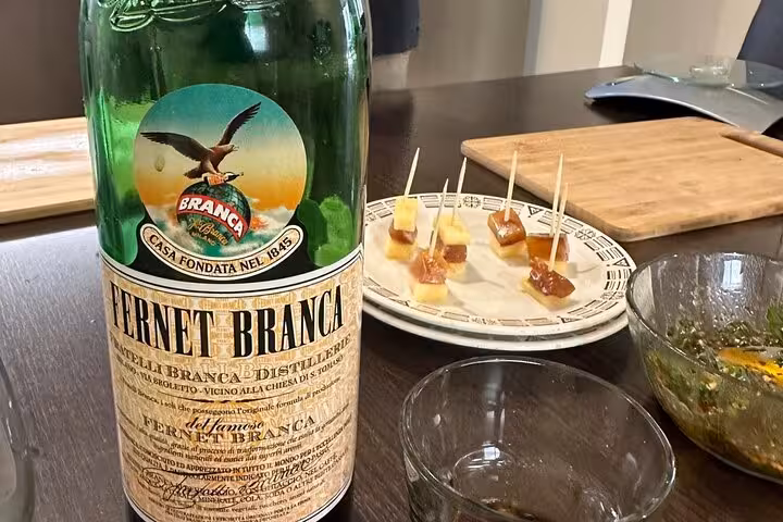 Fernet Branca bottle next to a plate of cheese and meat skewers, enhancing the Argentinian tasting session.