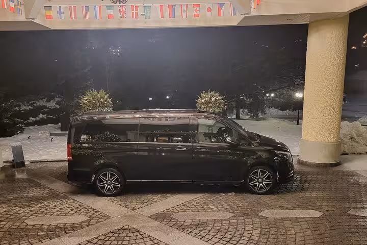 Black Mercedes minivan waiting outside hotel for private transfer service from Lucerne to Zurich with driver