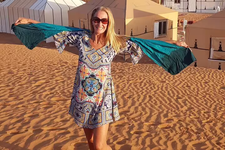 Traveler at Merzouga desert camp on 3-day private tour from Marrakech, enjoying Sahara dunes at sunset