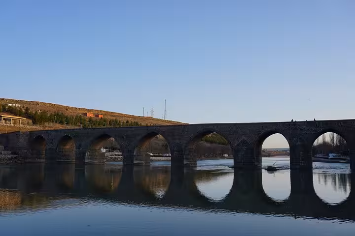 Historic stone arch bridge over a calm river at dusk, highlight of a 10-day all-inclusive Mesopotamia tour