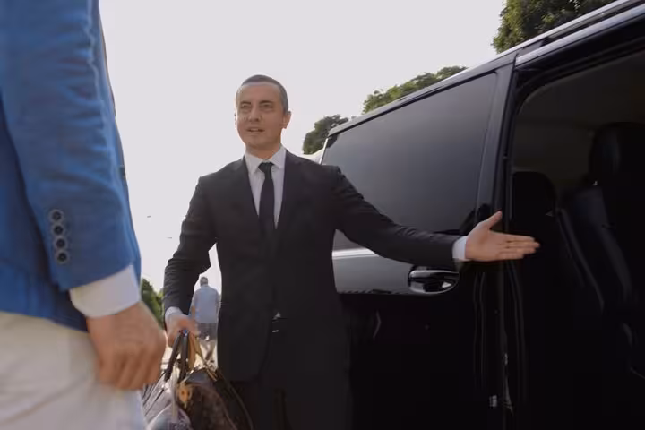 Professional chauffeur greeting passenger for Mestre to Venice Airport transfer in luxury vehicle.