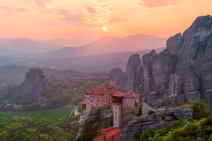 Sunset view of Meteora monastery atop cliffs on a full-day private tour from Athens with lunch included