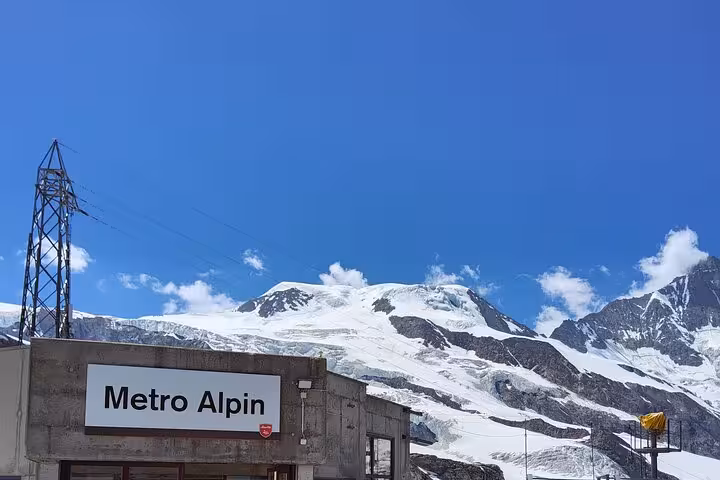 Metro Alpin sign at high-altitude station with glacier peaks, hidden gems on 4-day Swiss Alps tour