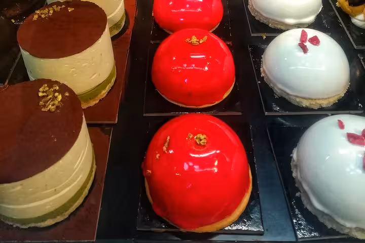 Colorful gourmet desserts including layered cakes and glossy domes, showcased in a Michelin restaurant in Rome.