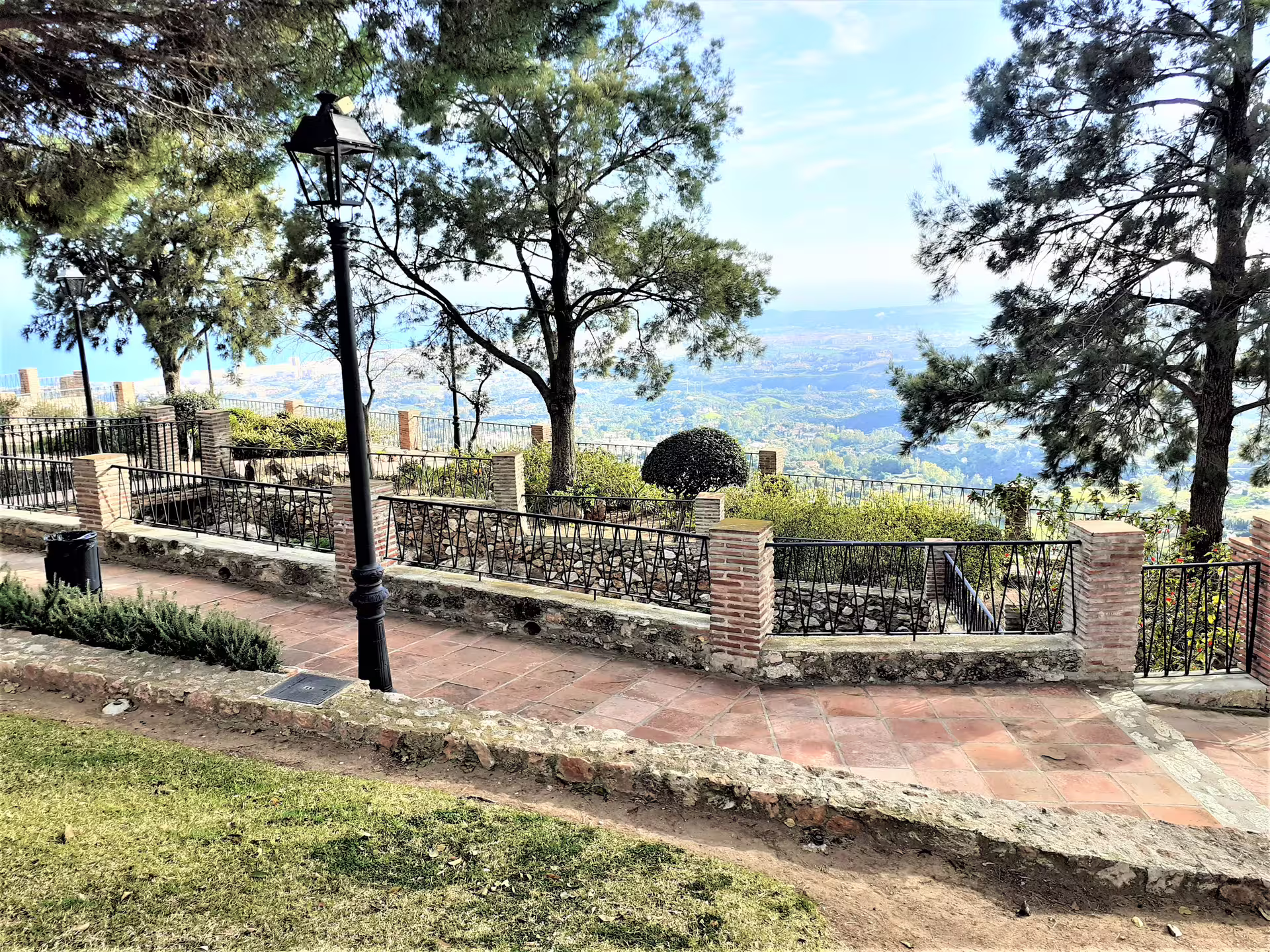 Scenic viewpoint stop on a Mijas group walking tour, with pine trees, terrace paths, and coastal views of Málaga
