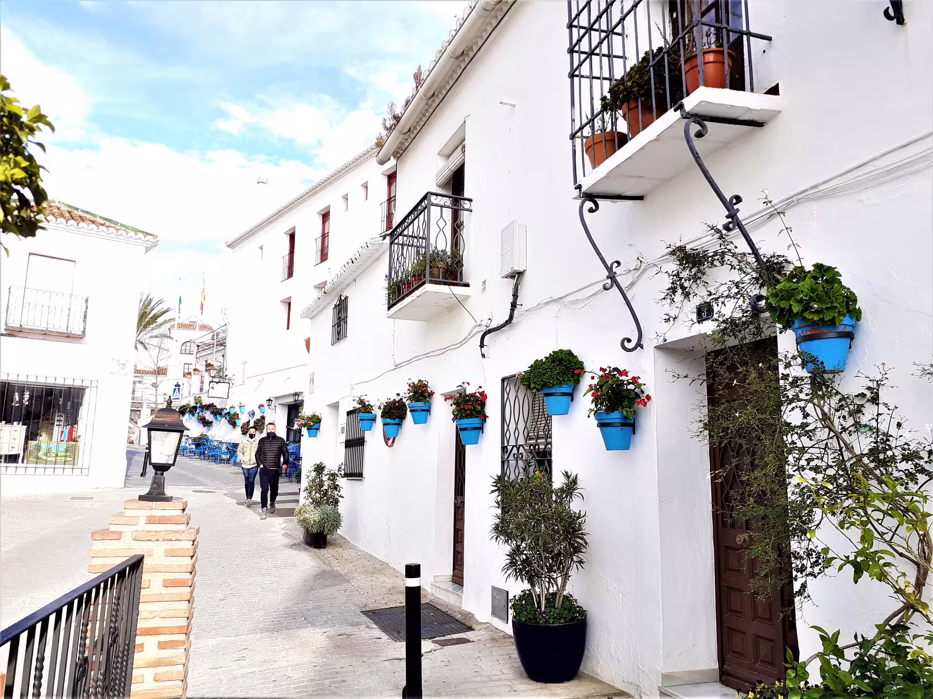 Mijas Pueblo group walking tour along a whitewashed street with blue flower pots, balconies, and Andalusian charm