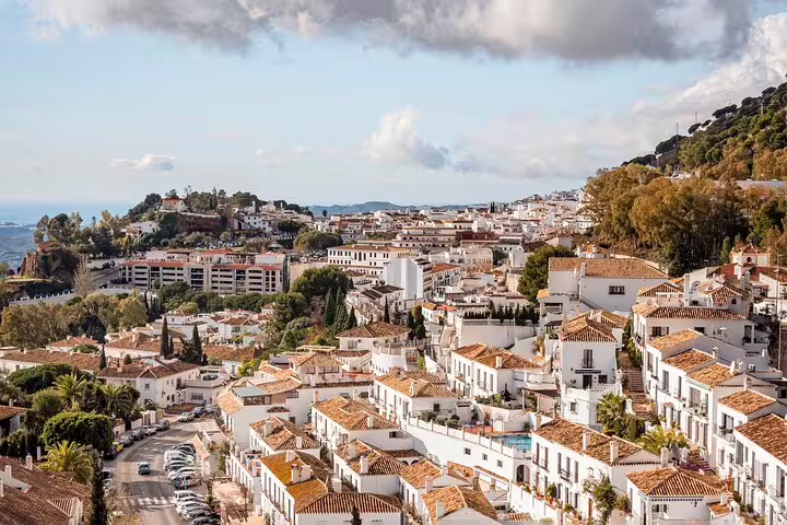 Scenic view of Mijas village's whitewashed buildings under a cloudy sky, perfect for a private guided tour.