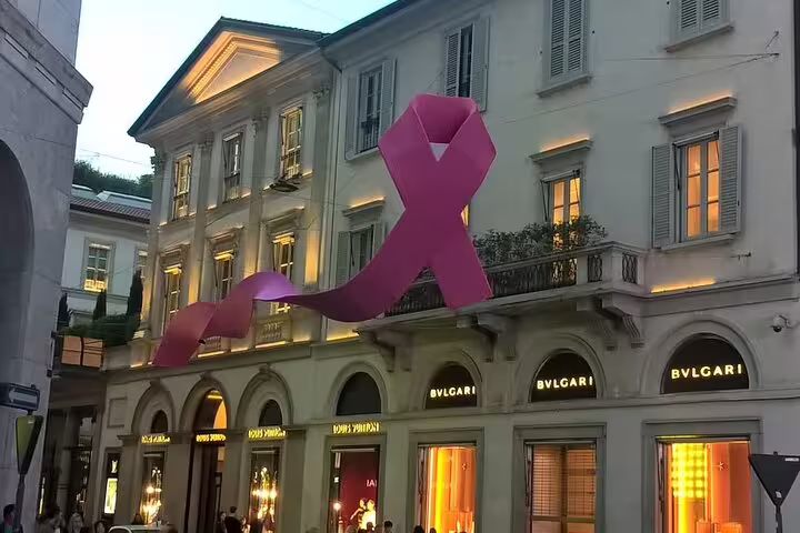 Elegant Milan building adorned with a large pink ribbon, showcasing luxury boutiques, perfect for a private full-day tour.