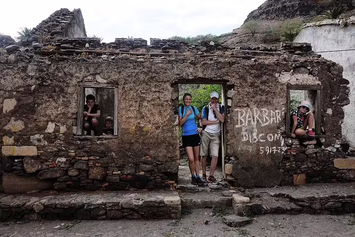 Tourists explore historic stone ruins in Mindelo, São Vicente, showcasing island's cultural and architectural heritage.