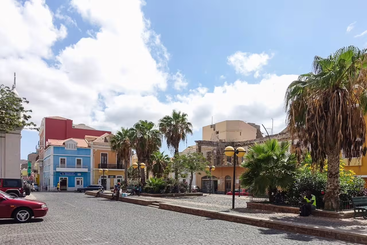 Colorful colonial buildings and palm trees line a cobblestone street in Mindelo, São Vicente, perfect for a shore excursion.