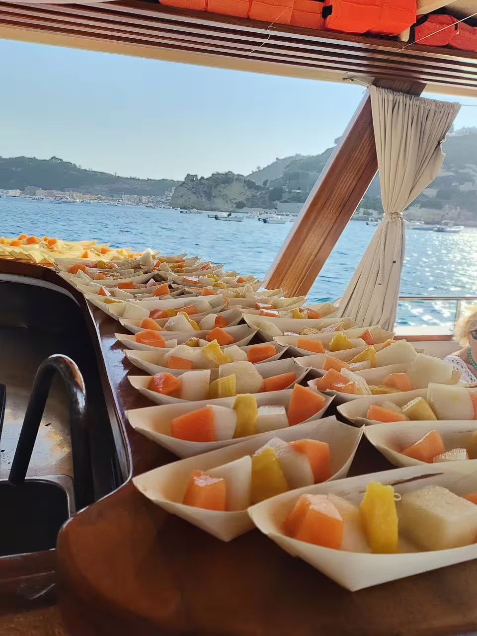 Aperitivo con frutta fresca servita a bordo durante Minicrociera Flegrea, panorama sul Golfo di Napoli