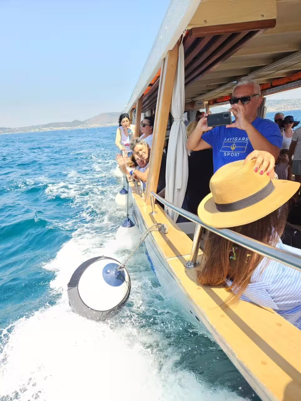 Passengers photographing the coast from the boat on Minicrociera Flegrea, sailing the Gulf of Naples near Campi Flegrei