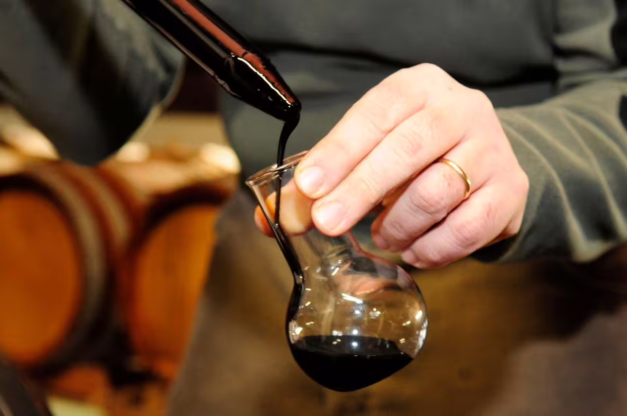 Pouring aged balsamic vinegar into tasting glass in a Modena vinegar cellar tour with aperitif experience
