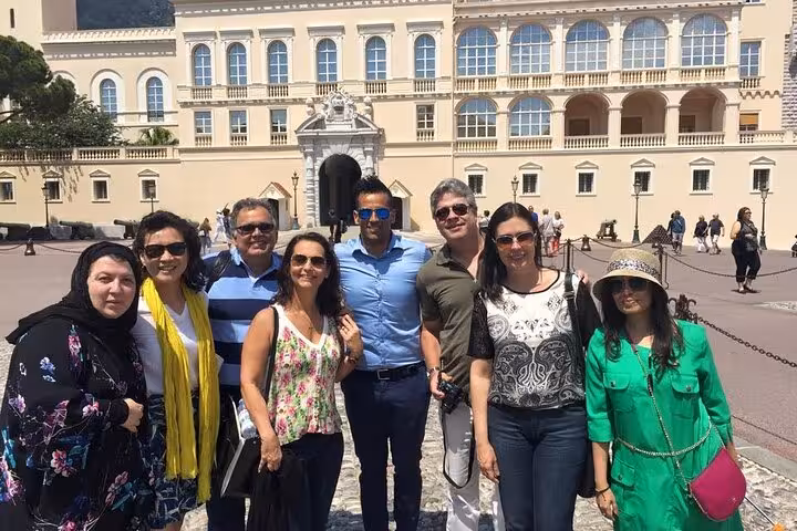 Group of tourists posing in front of Monaco's Prince's Palace, showcasing the grandeur of Monte-Carlo's architecture.