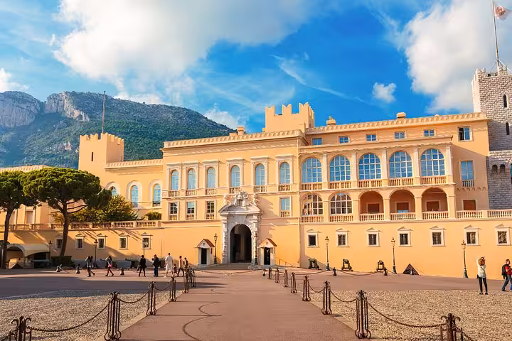 Bright facade of Monaco's royal palace under a vibrant blue sky, surrounded by scenic landscapes.
