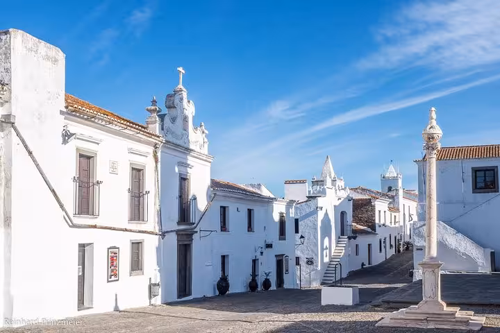 Charming whitewashed architecture of Monsaraz village under a clear blue sky, a highlight of the Évora walking tour.