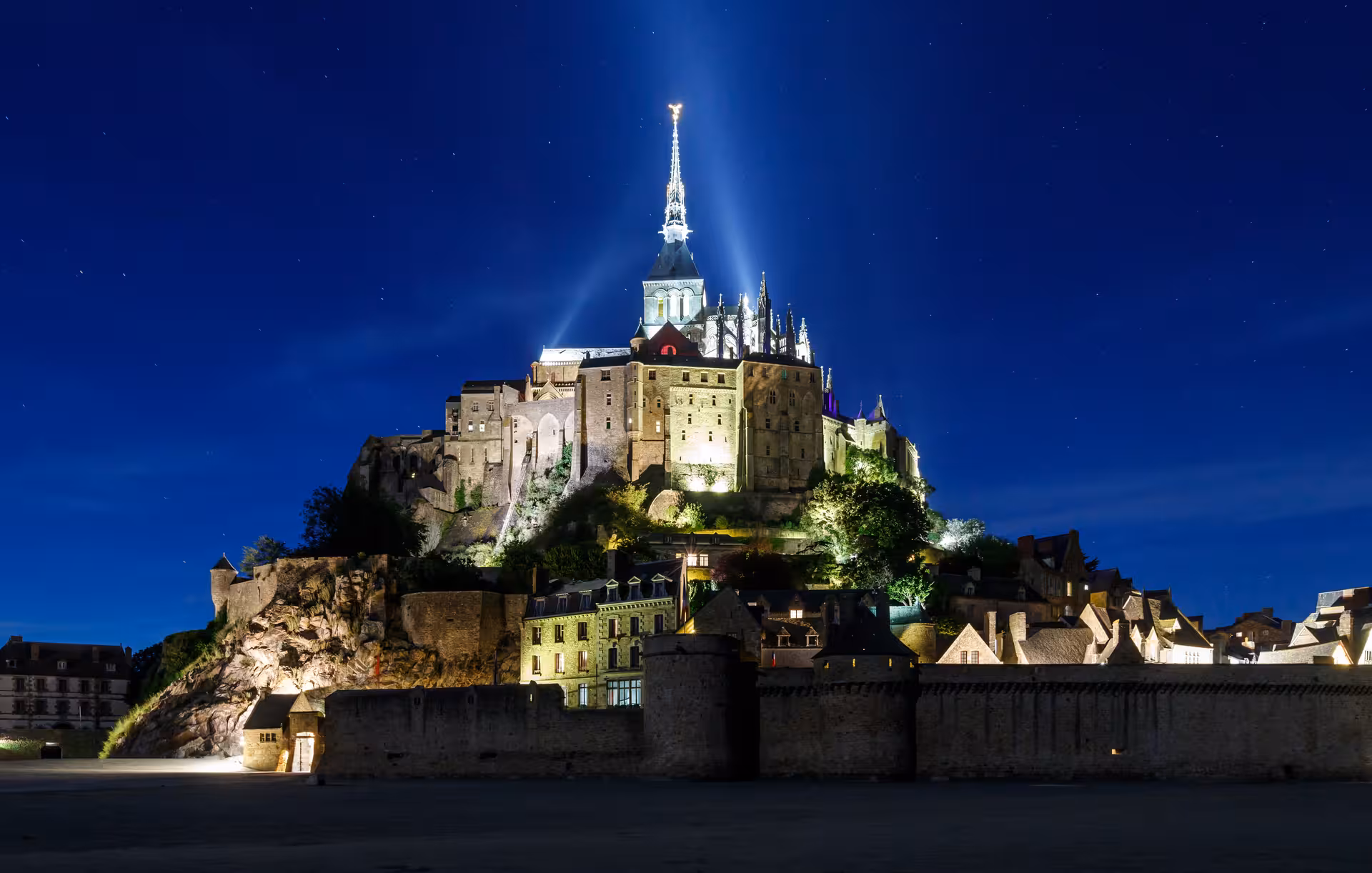 Mont Saint-Michel abbey illuminated at night, highlight of Normandy coast day trip by luxury minivan