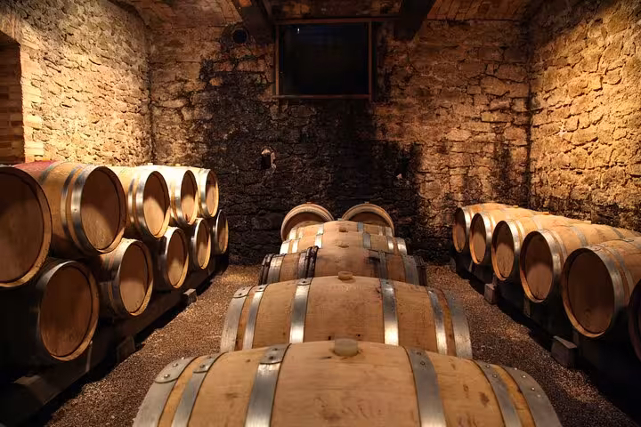 Rustic wine cellar with wooden barrels in Montalcino, Tuscany, offering wine tasting experiences on a private day trip.