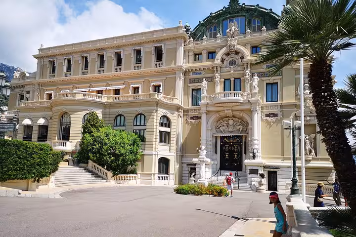 Monte Carlo Casino facade in Monaco on a Half Day Eze and Monaco tour from Nice, with palm trees and plaza
