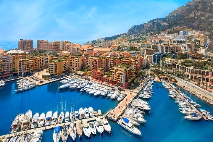 Scenic view of Monte-Carlo's luxurious harbor filled with yachts against a backdrop of vibrant buildings and hills.