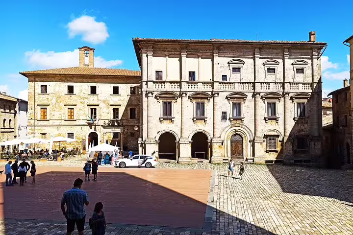 Sunlit medieval piazza in Montepulciano with Renaissance palaces and locals strolling on a private Cortona art and wine tour