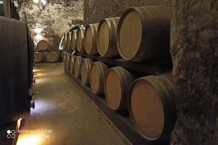 Aged oak wine barrels in an atmospheric Montepulciano cellar visited during the private Tuscan art and wine tasting tour