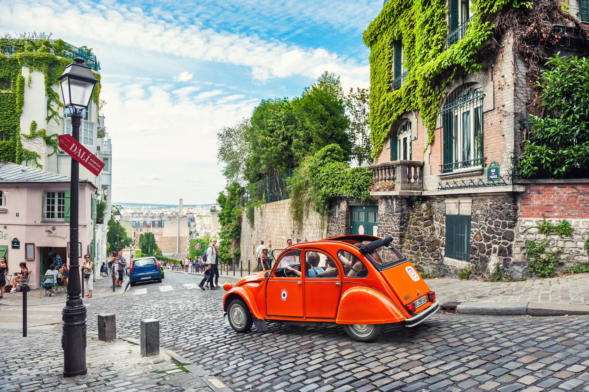 Cobblestone Montmartre street with classic orange car and ivy walls, Paris walking tour audioguide