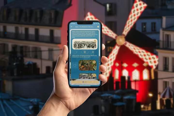 Montmartre GPS walking tour app displayed on smartphone with iconic Moulin Rouge windmill glowing red in Paris background