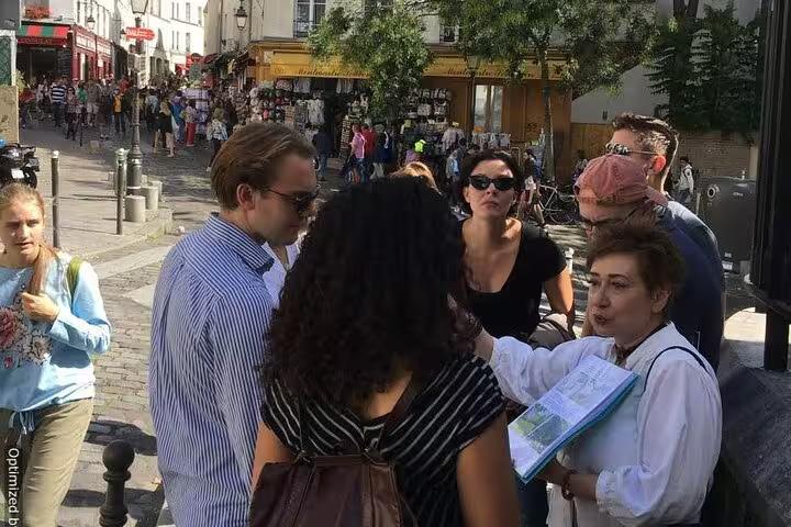 Small tour group exploring busy Montmartre streets in Paris during a self-guided GPS smartphone walking tour experience
