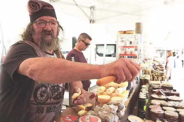 Local vendor offering a variety of artisanal cheeses at Montserrat market during a private tour with La Moreneta access.