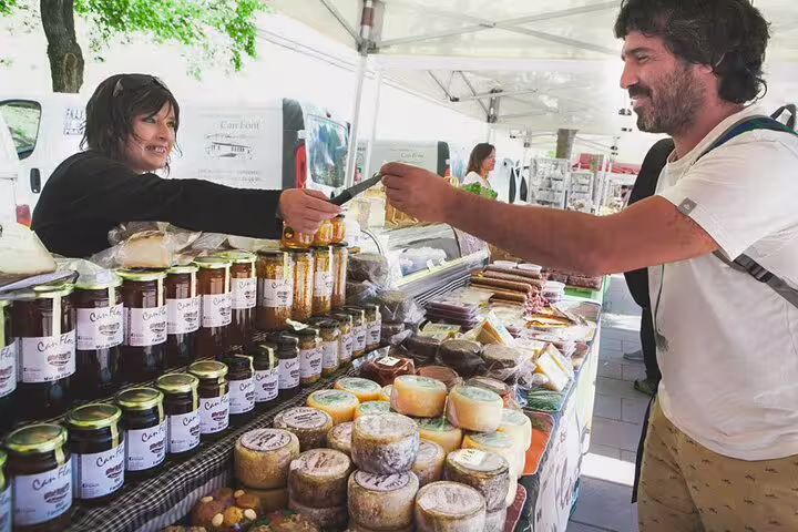 Tourist purchasing local products at a Montserrat market stall during a private tour with La Moreneta access and hotel pickup.