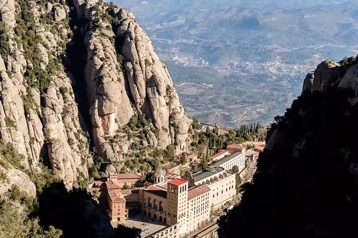 Aerial view of Montserrat Monastery nestled in rugged mountain landscape with panoramic views of Catalonia's countryside.