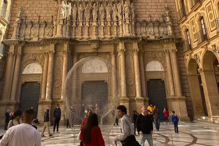 Visitors explore the ornate facade of Montserrat Monastery's basilica, highlighting its intricate architectural details.