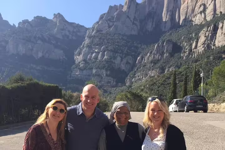 Group of tourists enjoying a sunny day with Montserrat mountain peaks in the background.