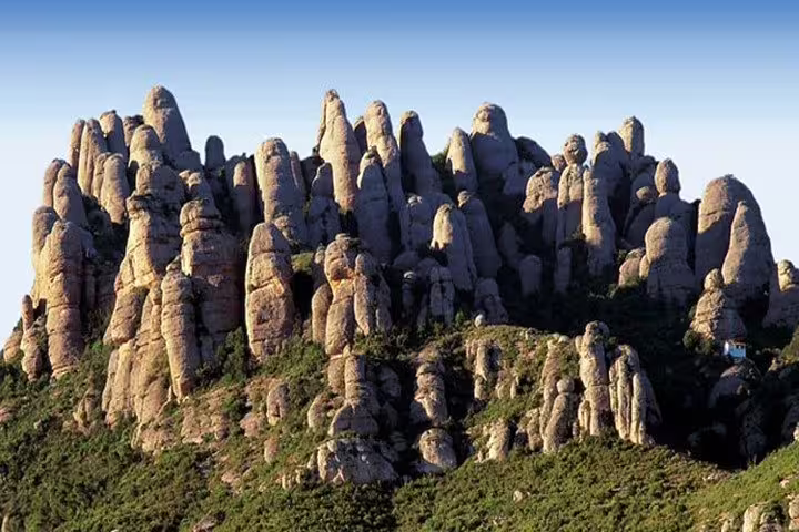 Majestic rock formations of Montserrat under a clear blue sky, ideal for hiking and nature tours.